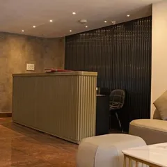 The reception desk, featuring a clean, fluted design against a textured concrete wall. The minimalist approach keeps the focus on service and efficiency.