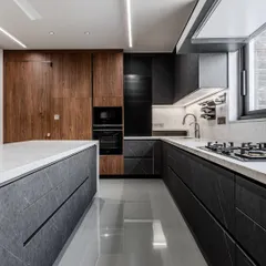 A full view of the handle-less island kitchen in Ahmedabad, showing the beautiful balance between the dark, textured cabinets and the light, continuous quartz surfaces.