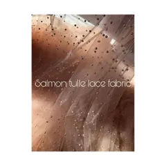 A swatch of delicate salmon tulle lace fabric, dotted with shimmering pearls. This material is chosen for its ethereal quality, perfect for creating couture gowns with a touch of magic.