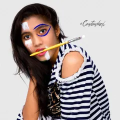 This creative portrait combines fashion with art, featuring a model with bold face paint. The pose and studio lighting are designed to create a high-fashion, editorial feel that is both intriguing and visually compelling.