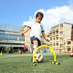Learning agility and ball control is fun with our kid-friendly equipment. This young athlete is practicing maneuvering the ball through a mini-hurdle, a key drill for developing coordination.
