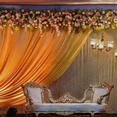 An elegant and classic stage design for a reception. I used a golden fabric drape on one side, complemented by a thick floral border on top and ornate chandeliers on the other side for a royal look.