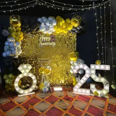 For a glamorous 25th-anniversary party, I created this stunning photo booth. It features a floor-to-ceiling gold shimmer wall, a balloon garland, a "Happy Anniversary" sign, and large marquee lights shaped like the number "25" and a diamond ring.