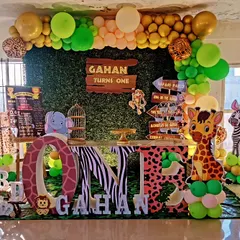 An exciting jungle-themed first birthday setup. We included a 'Wild One' backdrop, a faux grass floor, large 'ONE' letters with animal prints, and character cutouts of a lion, monkey, and giraffe to bring the safari to the party.