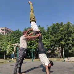 A three-person acro yoga stack, demonstrating advanced balance and strength. I'm in a handstand, supported by one partner, who is in turn supported by another.