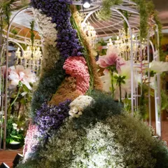 A stunning artistic installation featuring a dress form completely covered in a tapestry of pastel-colored flowers and moss. This unique piece served as a major photo-op and conversation starter.