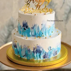 A two-tier cake with a beautiful blue watercolor effect, perfect for a 25th birthday. This was a Kulfi Falooda flavored cake, bringing a unique Indian fusion taste to the celebration.