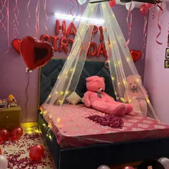 A slightly different angle of the romantic birthday room, showing the heart-shaped foil balloons and hanging ribbons from the ceiling balloons.