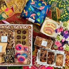 A complete celebration spread showcasing the variety we offer. This custom Diwali hamper includes a hand-decorated bento cake, assorted tea cakes, themed icing cookies, chocolate nut clusters, and fresh flowers, all arranged beautifully for gifting.