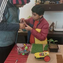 I believe in guiding, not doing. Here, I'm helping a student assemble the electronic components for his solar-powered car, part of his sustainable city project. He learned about circuits and renewable energy firsthand.