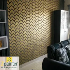 A striking geometric pattern in gold and charcoal gives this living room wall a modern, art-deco feel. This is an example of a metallic texture finish that catches the light beautifully.
