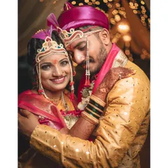A classic portrait of a bride and groom in their traditional Maharashtrian wedding attire, smiling brightly for the camera.