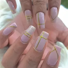 A sophisticated design on square-shaped nails, featuring a soft pink base with clean, geometric gold stripes for a modern and minimalist look.