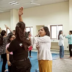 A female instructor guides participants through a blocking drill during a corporate workshop for women.