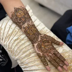 This is a classic Arabic floral henna design, perfect for festive occasions. The pattern flows from the forearm down to the fingers, featuring large, shaded roses and leafy vines with plenty of open skin for a bold contrast.