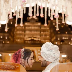 Under a beautifully decorated mandap with a grand palace illuminated in the background, the couple shares an intimate glance. This frame captures the romance and scale of a destination wedding in Jaipur.