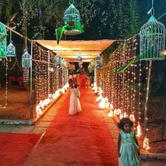 A magical evening walkway lined with curtains of fairy lights and decorated with hanging birdcages, creating an enchanting path for guests.