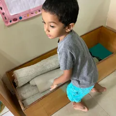 Independence in action. This child is selecting a work mat from the low, accessible shelves, demonstrating his ability to make choices and initiate his own learning activities within our prepared environment.