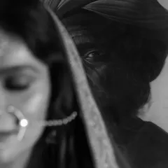 A powerful black and white artistic portrait. The focus is sharp on the background painting while the bride is softly blurred, creating a moody and intriguing composition.