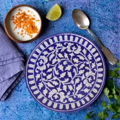 An overhead shot of a beautiful blue and white ceramic plate, styled with Indian food. This shows the plate in its intended use, making it more appealing to customers.