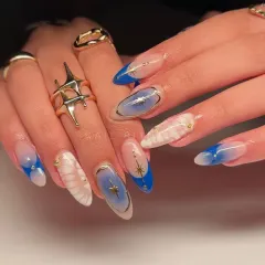 A closer look at our cosmic manicure. This image highlights the beautiful blend of blue aura, white marble, and gold star designs.