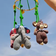 A view of the jungle mobile from below, showing the elephant and monkey characters hanging from the vine-wrapped wooden hoop.
