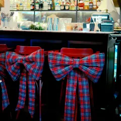 Bar stools at Scarlett House are dressed up for the holidays with large, festive plaid bows, ensuring every corner of the venue feels celebratory.