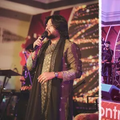 A close-up of our lead singer Alish Mohan, with the band visible in the background. This shot highlights the frontman while acknowledging the full team that supports him.