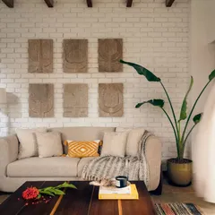 Unveiling a hidden sanctuary in Goa. This living space at Villa Shai seamlessly blends nature, comfort, and sustainable living, with an exposed brick wall, natural wood beams, and comfortable furnishings that invite relaxation.