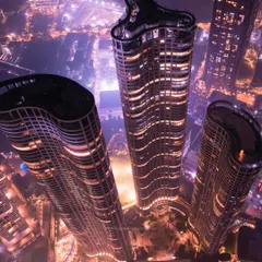 A closer aerial shot of the Lodha Park towers. This perspective highlights the curves and lines of modern architecture, lit up against the night sky.