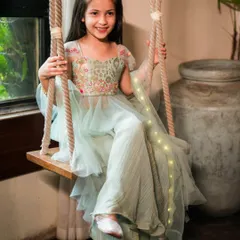 A whimsical moment from a kids' couture shoot. The swing adds a touch of playfulness, and the soft lighting from the window beautifully illuminates the little model and her fairy-tale dress.