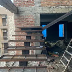 The raw metal framework of a cantilevered staircase during construction. This shows the essential structural engineering that underpins the minimalist final design.