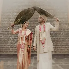 A playful and creative portrait of a South Indian couple. Using traditional hand fans, they create a heart shape above them, smiling at each other.