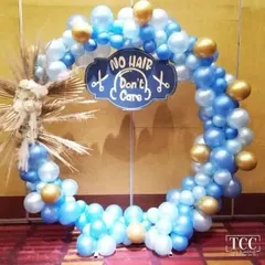 A fun and unique backdrop for a baby's mundan or first haircut ceremony, with a 'No Hair Don't Care' sign on a blue and gold balloon ring.