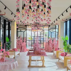 A complete venue transformation for a celebrity influencer's event, featuring a striking monochromatic pink theme. The space is filled with pink velvet textures, custom floral chandeliers with hanging Edison bulbs, and elegant lounge seating, creating a dreamy and modern aesthetic.