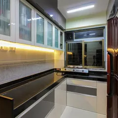 A practical kitchen with a black granite countertop and a mix of grey and white cabinets. The frosted glass on the upper cabinets adds a touch of lightness to the design.