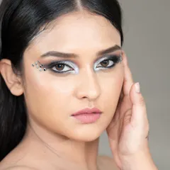 A close-up beauty shot showcasing a dramatic silver eye makeup look with crystal embellishments. This type of detailed work is ideal for makeup artists' portfolios and cosmetic campaigns.