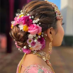 A vibrant and full floral bun, using a mix of colorful fresh flowers. This hairstyle is a statement piece, perfect for a bride who wants a bold and beautiful look.