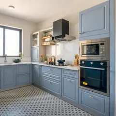 This U-shaped kitchen features a classic look with powder-blue shaker cabinets and a patterned tile floor. I integrated the oven and microwave into a tall unit to save counter space.