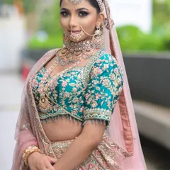 A stunning look in a teal and pink lehenga. The makeup features dramatic smoky eyes and a perfectly contoured base, creating a confident and glamorous bridal style.
