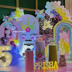 A vibrant and magical unicorn-themed party with a shimmery backdrop, rainbow balloon arches, and a large light-up number '5'.