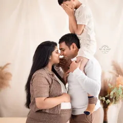 The whole family is part of the journey. This heartwarming family maternity photo captures a playful and intimate moment between the parents and the excited older sibling, celebrating the love that's about to grow.
