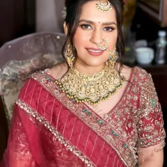 This front-facing portrait shows the complete bridal look. The makeup is balanced, with attention to both the eyes and lips, and the hair is elegantly swept up to showcase her jewelry.