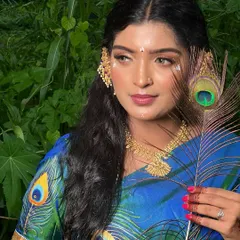 A creative look inspired by Radha, featuring a peacock feather. The makeup includes soft, glowing skin and artistic details on the face, perfect for a themed shoot or unique bridal look.