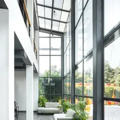 For the Media Monks campus, we designed a double-height glass atrium that floods the interior with natural light and seamlessly connects the workspace to the surrounding landscape. This architectural feature creates a sense of openness and transparency, fostering a collaborative and refreshing work environment.
