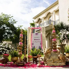 A detailed view of the beautiful welcome decor for Bhanu's ear piercing ceremony, featuring brass lamps, floral arrangements, and a personalized sign.