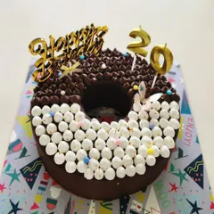 A fun, donut shaped cake for a 20th birthday celebration. This one combines two flavors, with one half decorated with rich chocolate piping and the other with soft vanilla marshmallows.