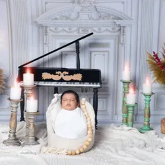 A swaddled newborn rests in a basket in front of the piano. The warm glow from the candles creates a serene and classical atmosphere.