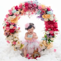 This little one is a picture of pure delight, laughing as she plays with a flower in our magical floral ring setup.