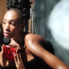 A moment captured on set just before the final shot. This shows the finished makeup look, featuring radiant skin and a high-fashion hair updo, ready for the camera.